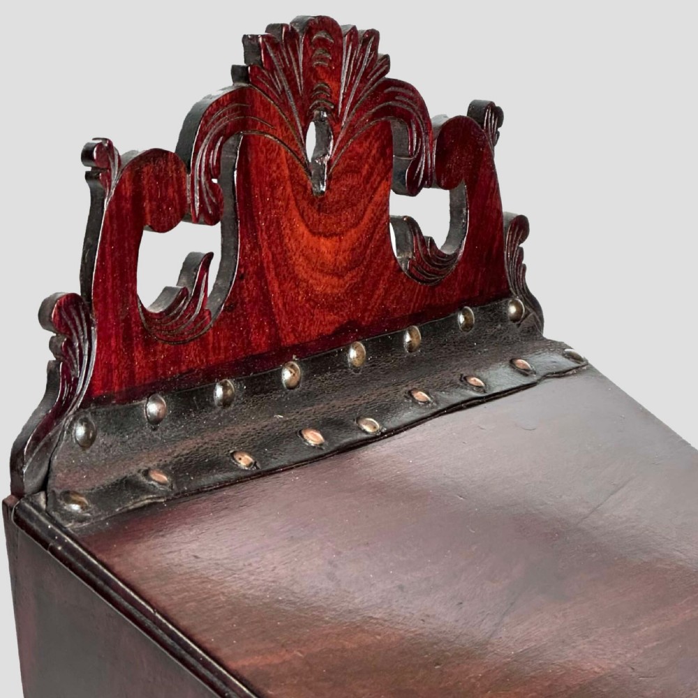 A Georgian mahogany wall-hanging cutlery box with a sloped lid, brass stud details, and a carved pierced crest. View III