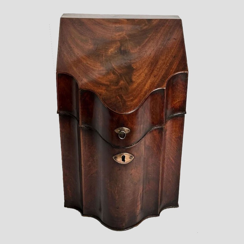 An antique Sheraton mahogany knife box featuring a sloped lid, serpentine shaped front, and a brass keyhole escutcheon. View II