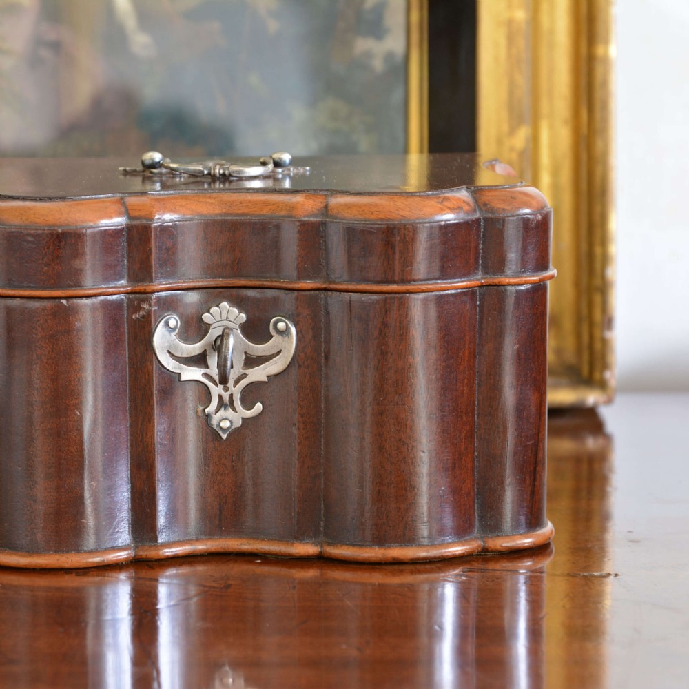 An early 18th-century shaped red walnut tea caddy featuring a top brass handle and a metal escutcheon with a key inserted. View II