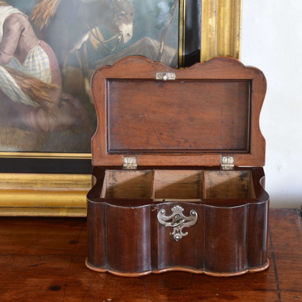 An early 18th-century shaped red walnut tea caddy featuring a top brass handle and a metal escutcheon with a key inserted. View VI