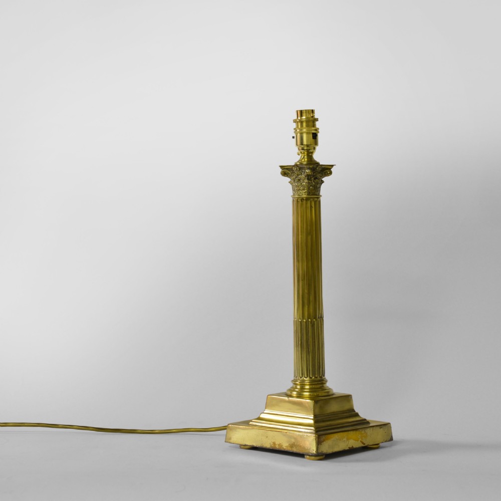 A Victorian cast brass table lamp featuring a fluted Corinthian column shaft topped with acanthus leaves on a stepped plinth.