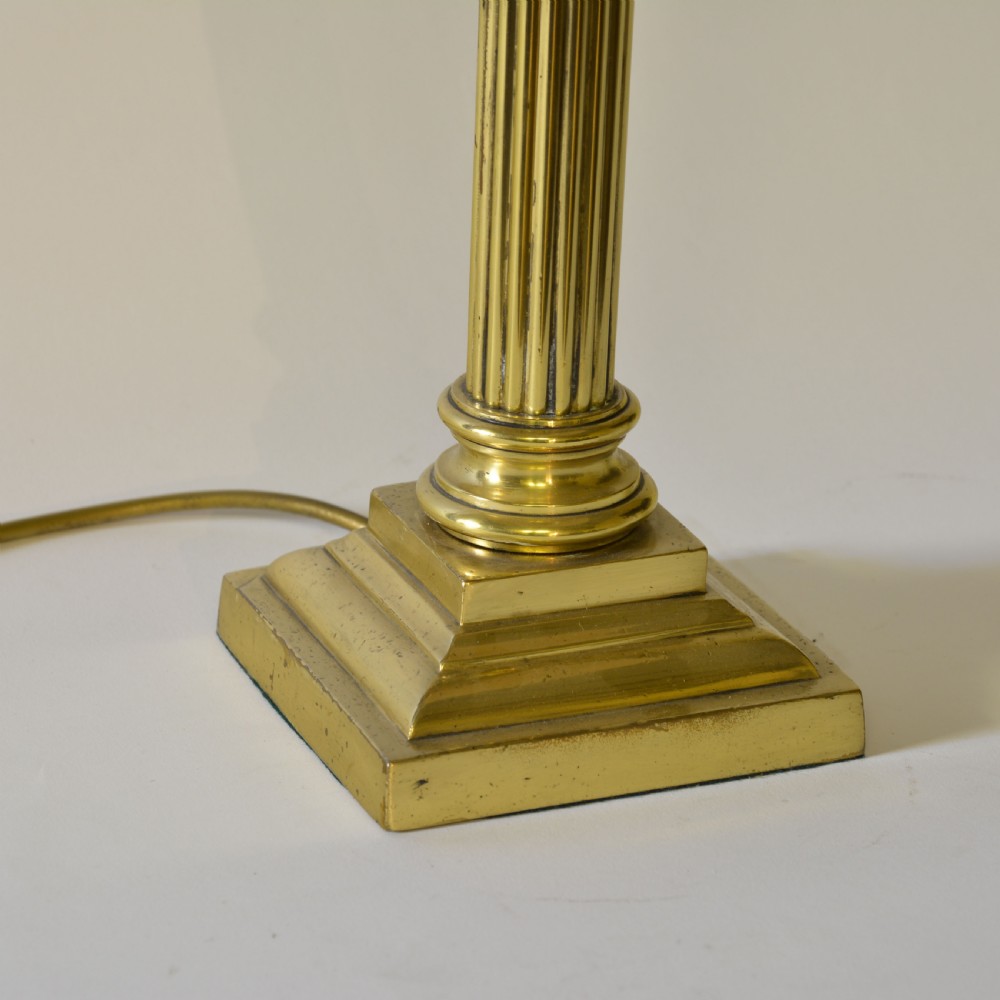 A Victorian brass table lamp designed as a fluted Corinthian column with a stepped base, topped with a pleated sage green fabric shade. View IV