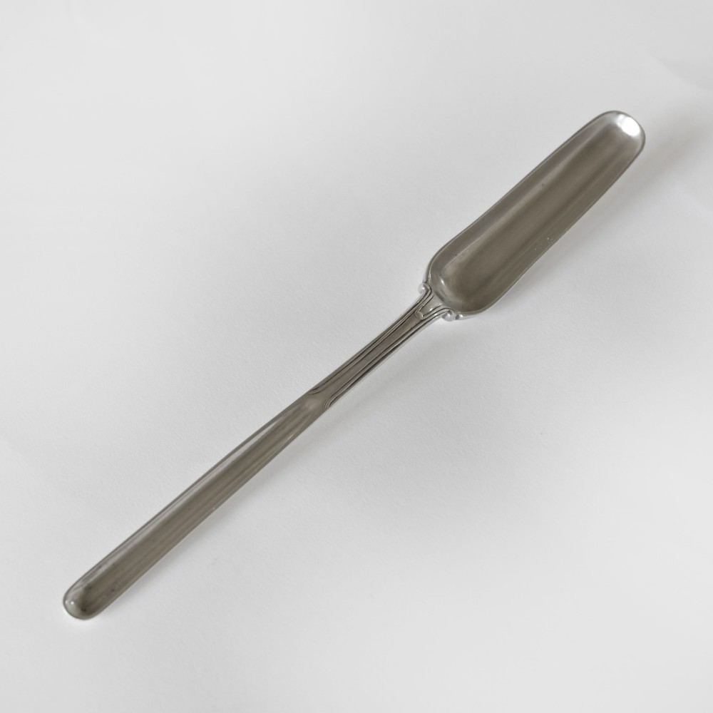 An English sterling silver marrow scoop with a long channelled bowl and a slender linear stem set against a plain light background.