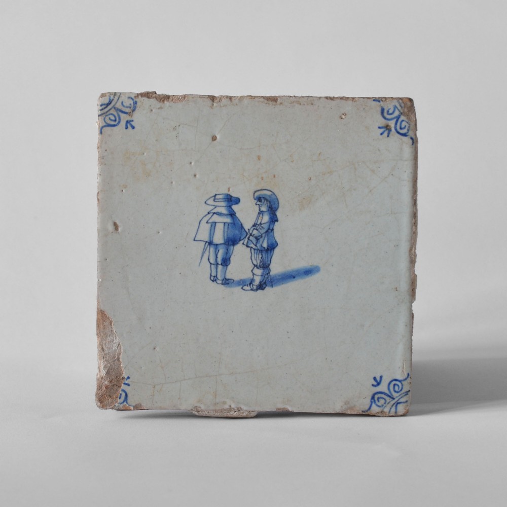 A square 18th-century Dutch Delft tile featuring hand-painted figures in cobalt blue on a crazed off-white tin-glazed earthenware surface with corner embellishments.
