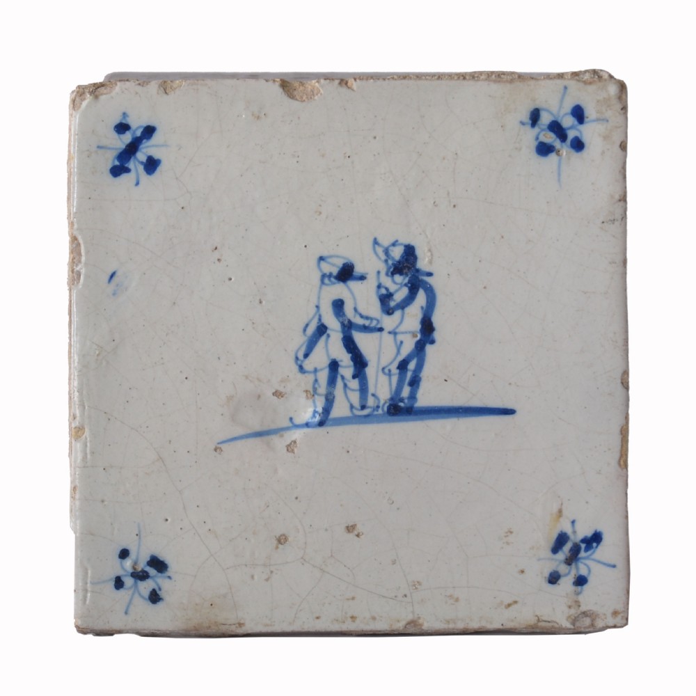 A square 18th-century tin-glazed earthenware tile decorated with hand-painted blue figures in the centre and small corner motifs against an off-white background. View III
