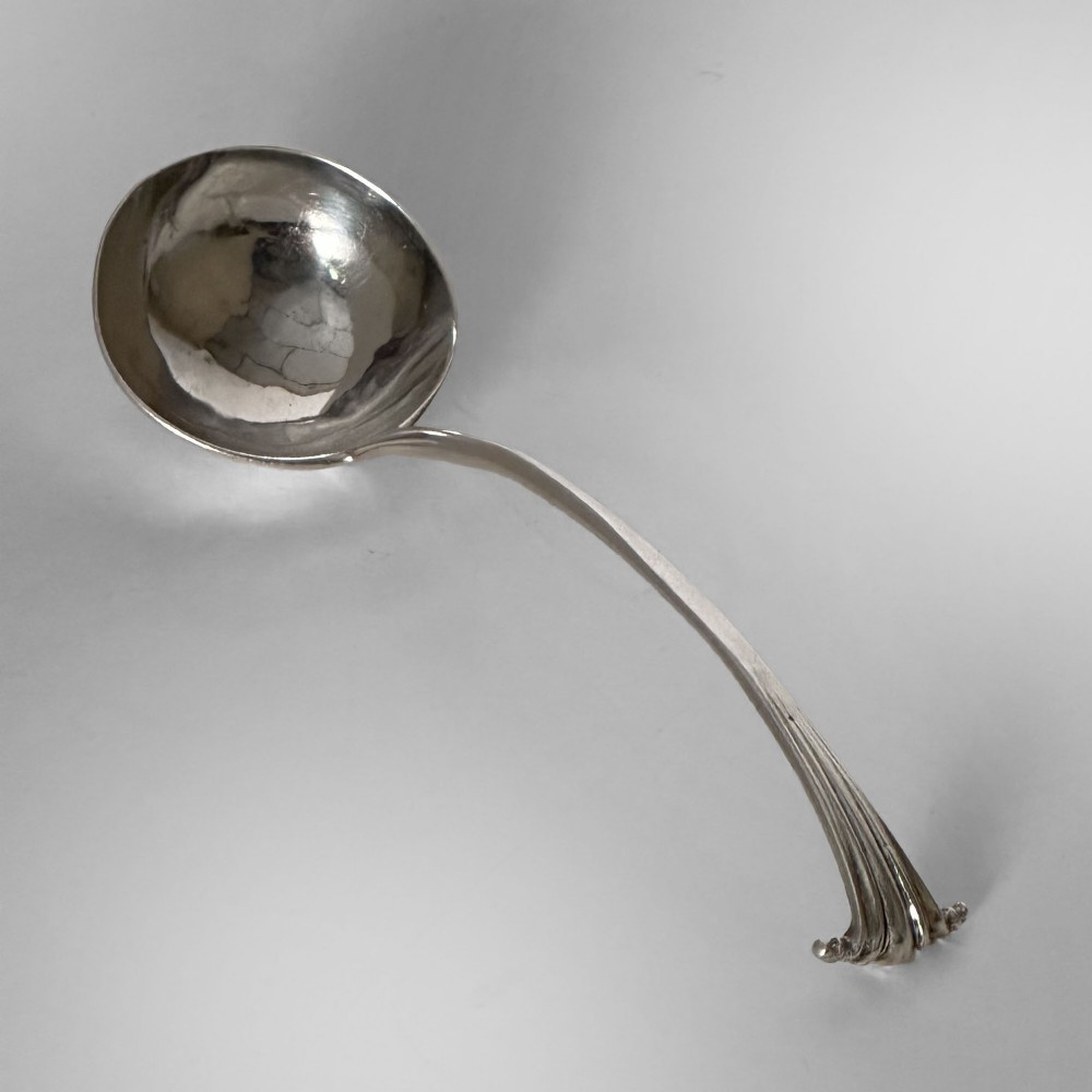 An 18th-century Georgian sterling silver ladle featuring a deep circular bowl and a curved handle with a scrolled terminal.