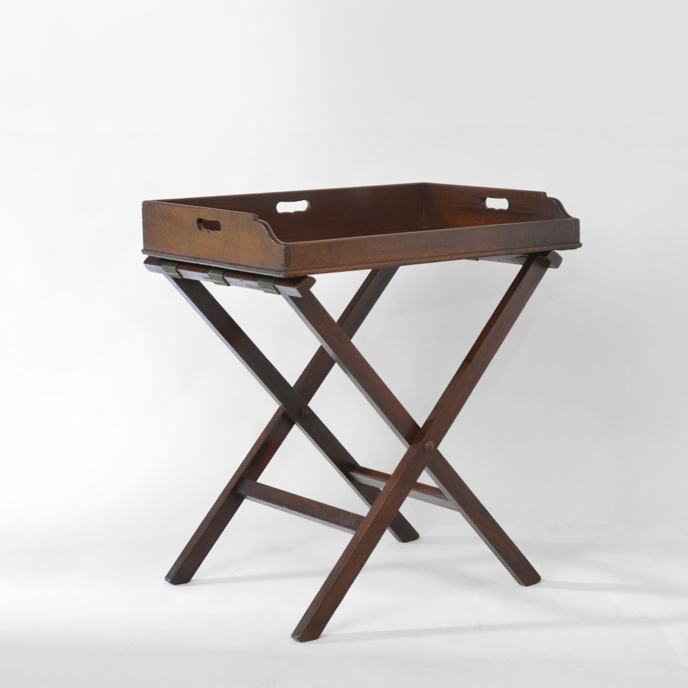 An 18th century Georgian mahogany butler tray featuring gallery sides with cut-out hand grips resting on a folding X-frame stand.