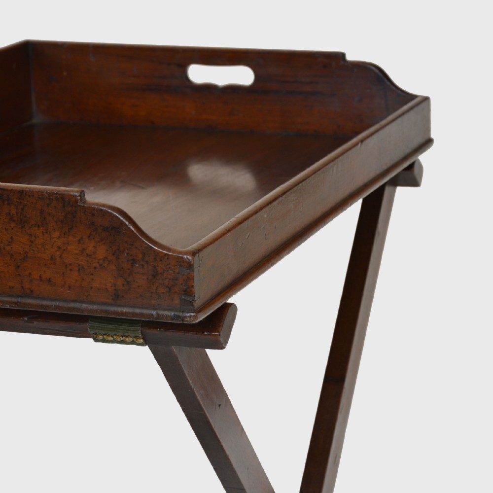 An 18th century Georgian mahogany butler tray featuring gallery sides with cut-out hand grips resting on a folding X-frame stand. View VII