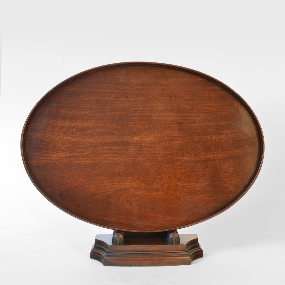 An eighteenth-century Georgian oval mahogany tray featuring a raised gallery rim and rich wood graining, displayed upright on a wooden base.