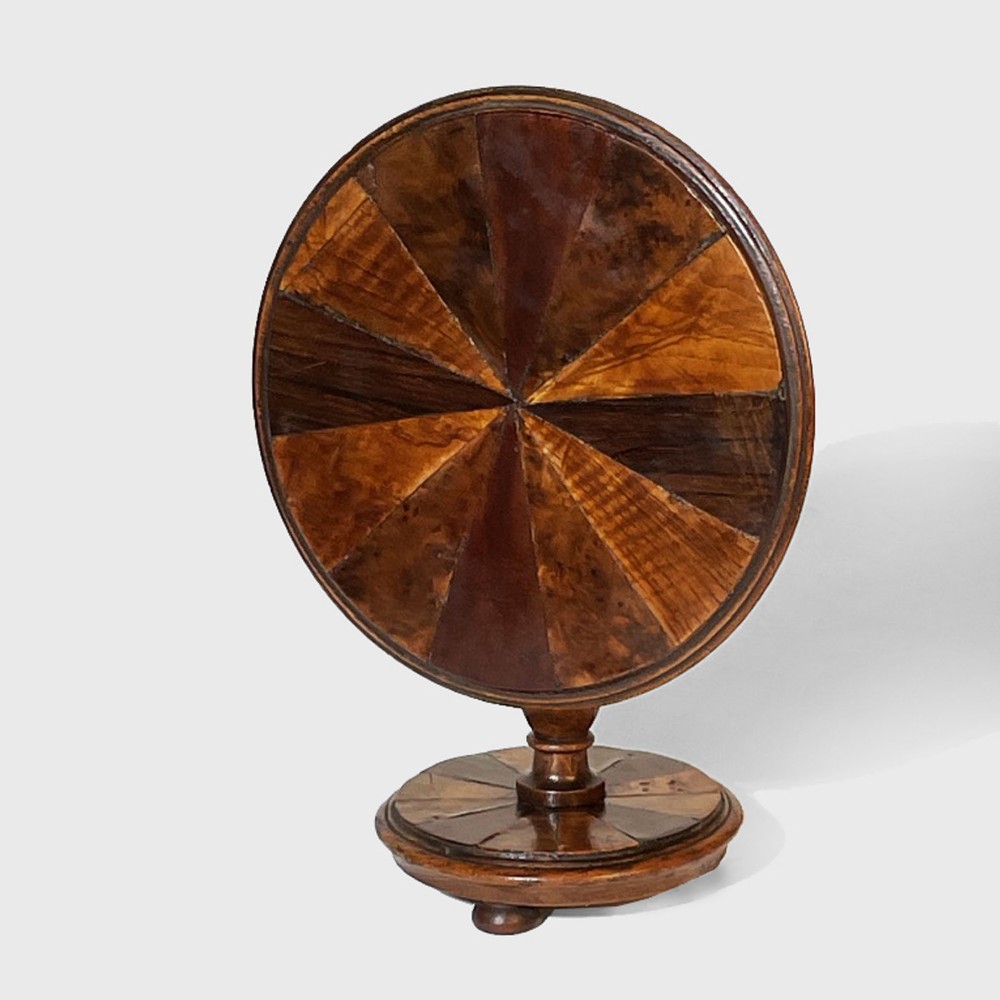 A 19th-century miniature circular tilt-top pedestal table featuring a radiating segmented parquetry pattern in varied wood veneers set upon a turned base.