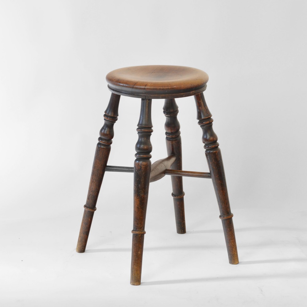 A 19th-century dark brown turned timber pub stool with a circular dished seat and an H-shaped stretcher.