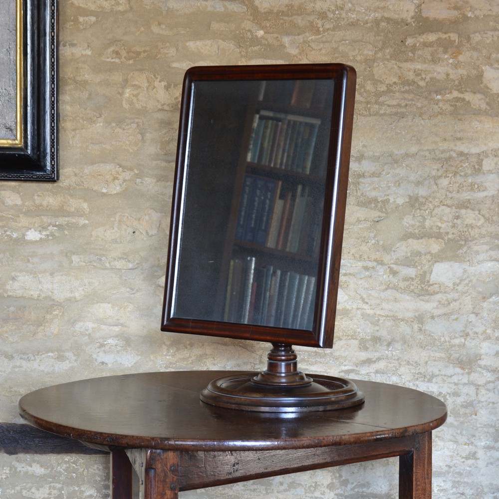 A seventeenth-century rectangular walnut and boxwood table mirror set on a turned pedestal stem and stepped circular base.