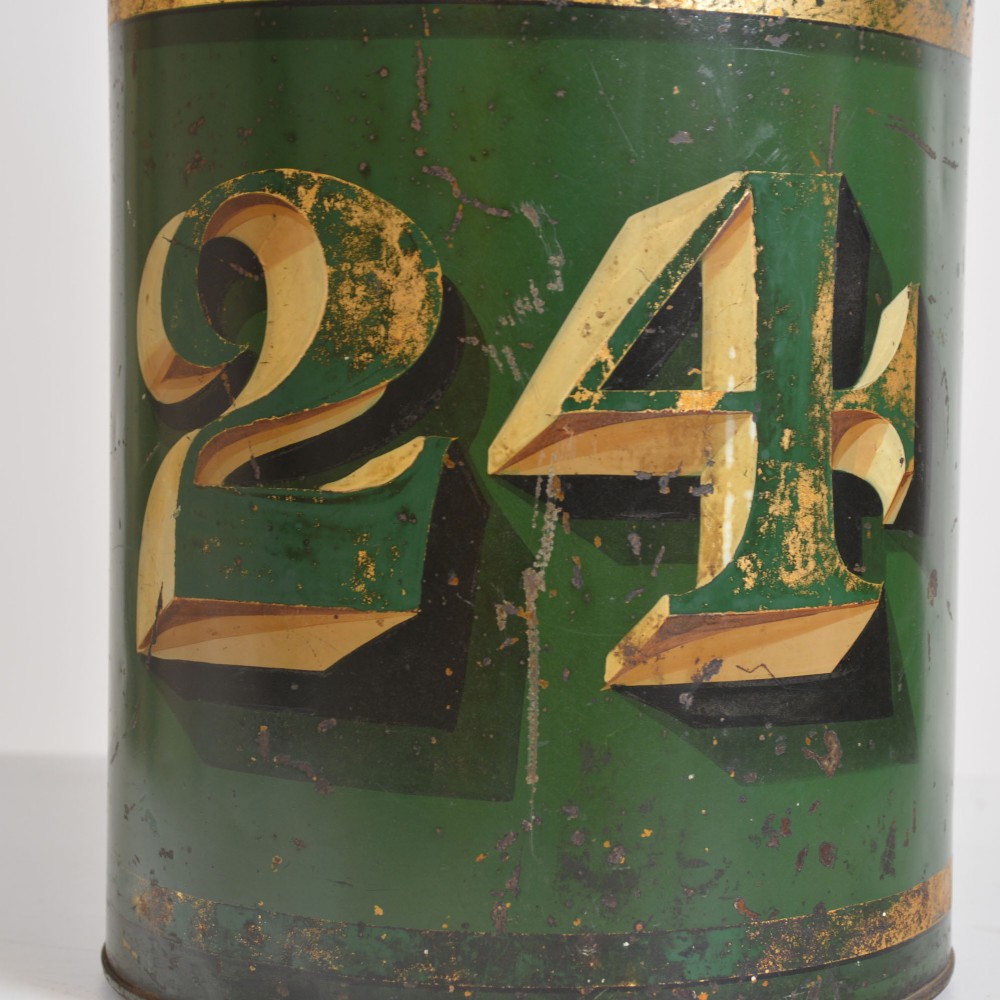 A cylindrical dark green antique tin tea canister featuring gilded bands and a prominent hand-painted number 24 on the front. View V