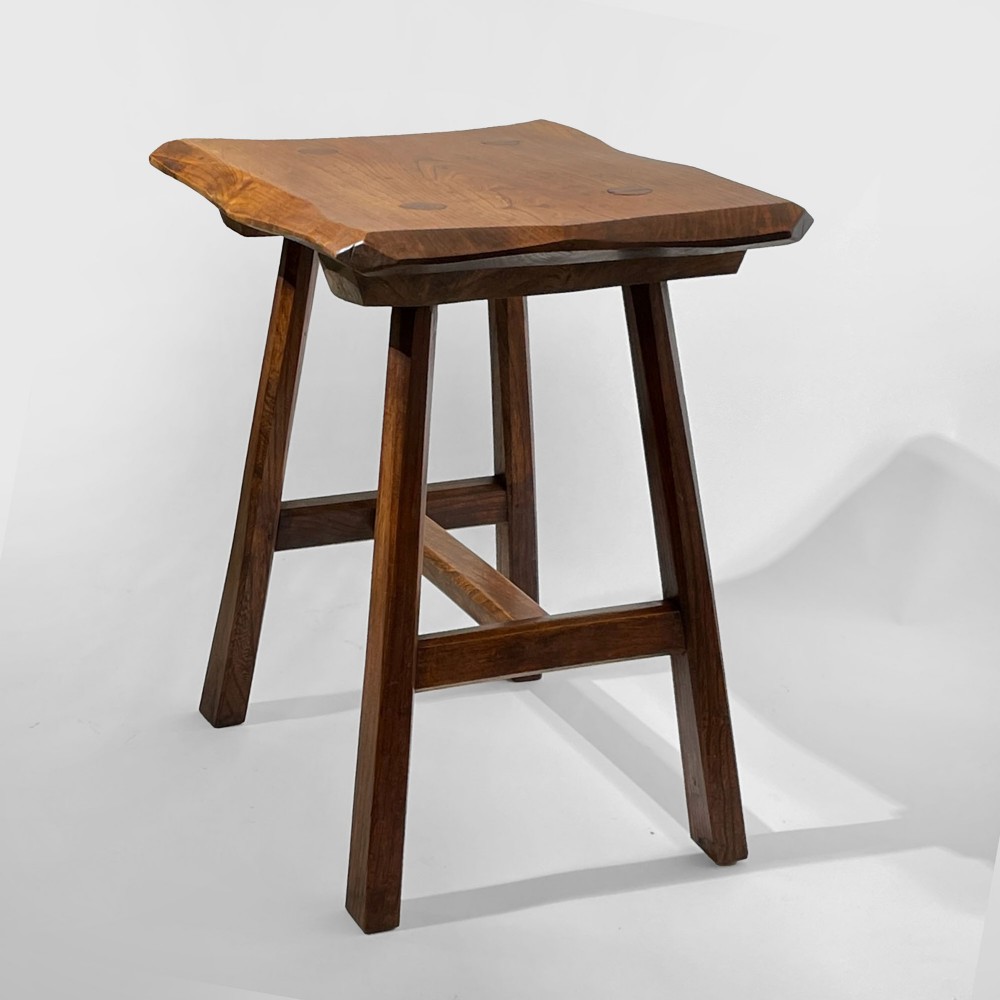 A rustic medium brown elm wooden stool featuring a carved rectangular top with exposed joinery and splayed legs with stretchers. View II