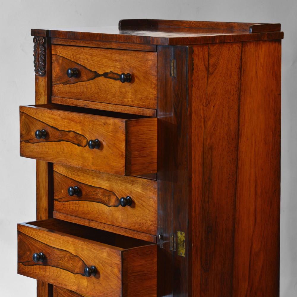 A 19th-century rosewood Wellington chest featuring six graduated drawers, turned wooden knobs, carved corbels, and a side-locking bar on a plinth base. View II