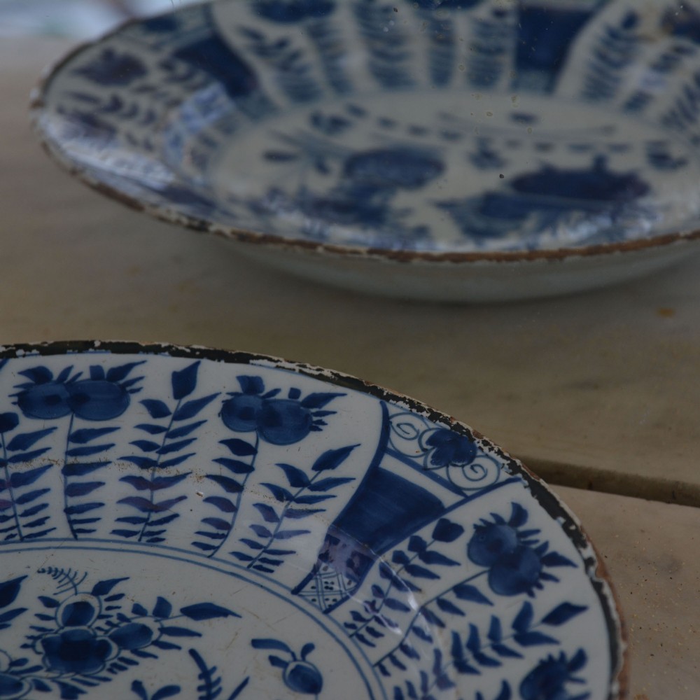 A circular tin-glazed earthenware charger featuring hand-painted cobalt blue urn and botanical motifs on a white background with a panelled rim. View IV