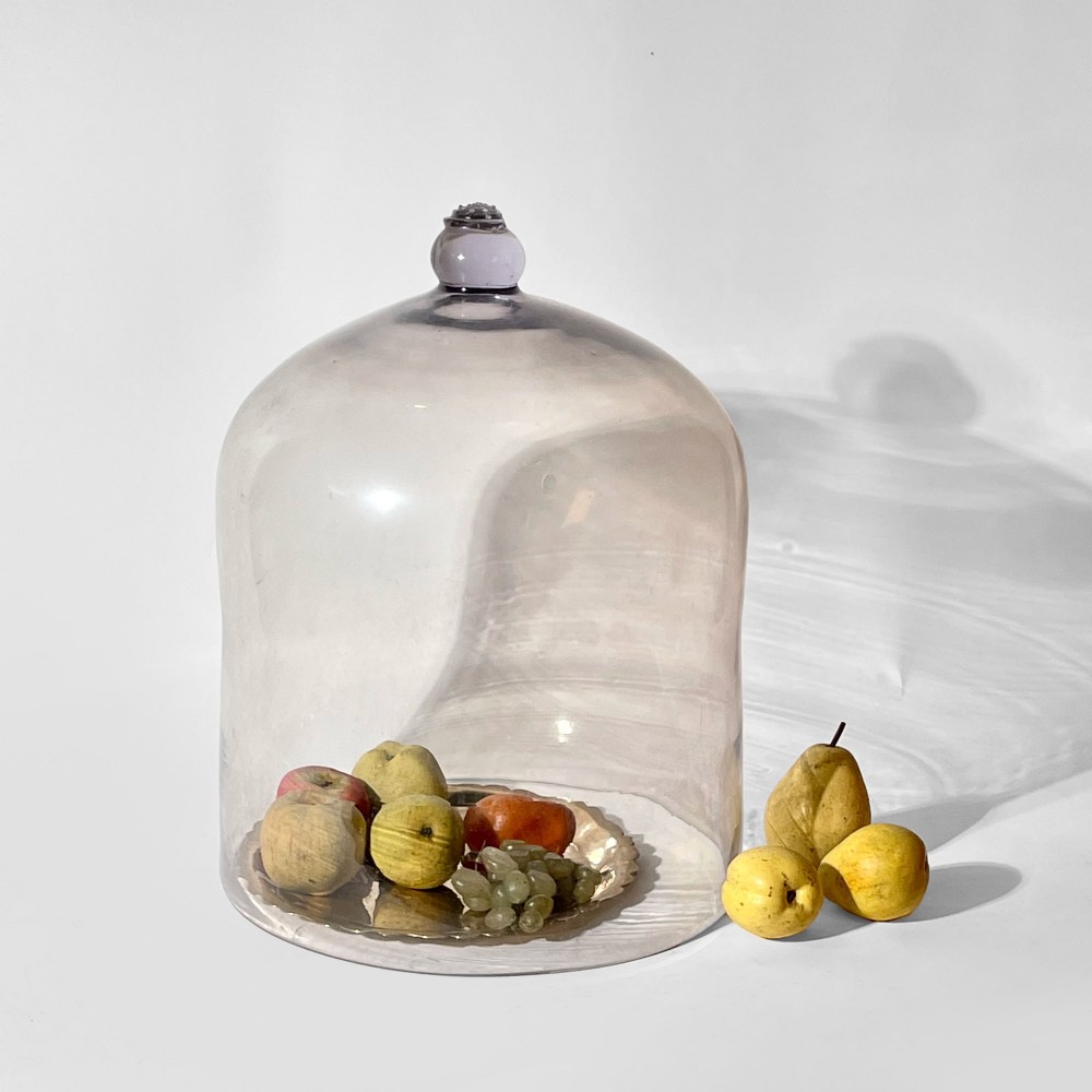 A large clear glass dome cloche featuring a smooth cylindrical body and a decorative glass knob finial on the top apex.