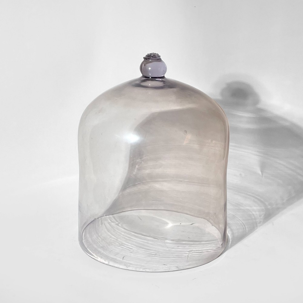 A large clear glass dome cloche featuring a smooth cylindrical body and a decorative glass knob finial on the top apex. View II