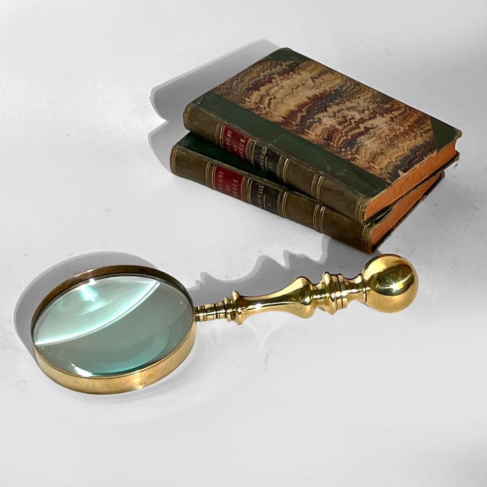 A 19th-century brass magnifying glass featuring a turned handle with a spherical finial and a circular convex lens.