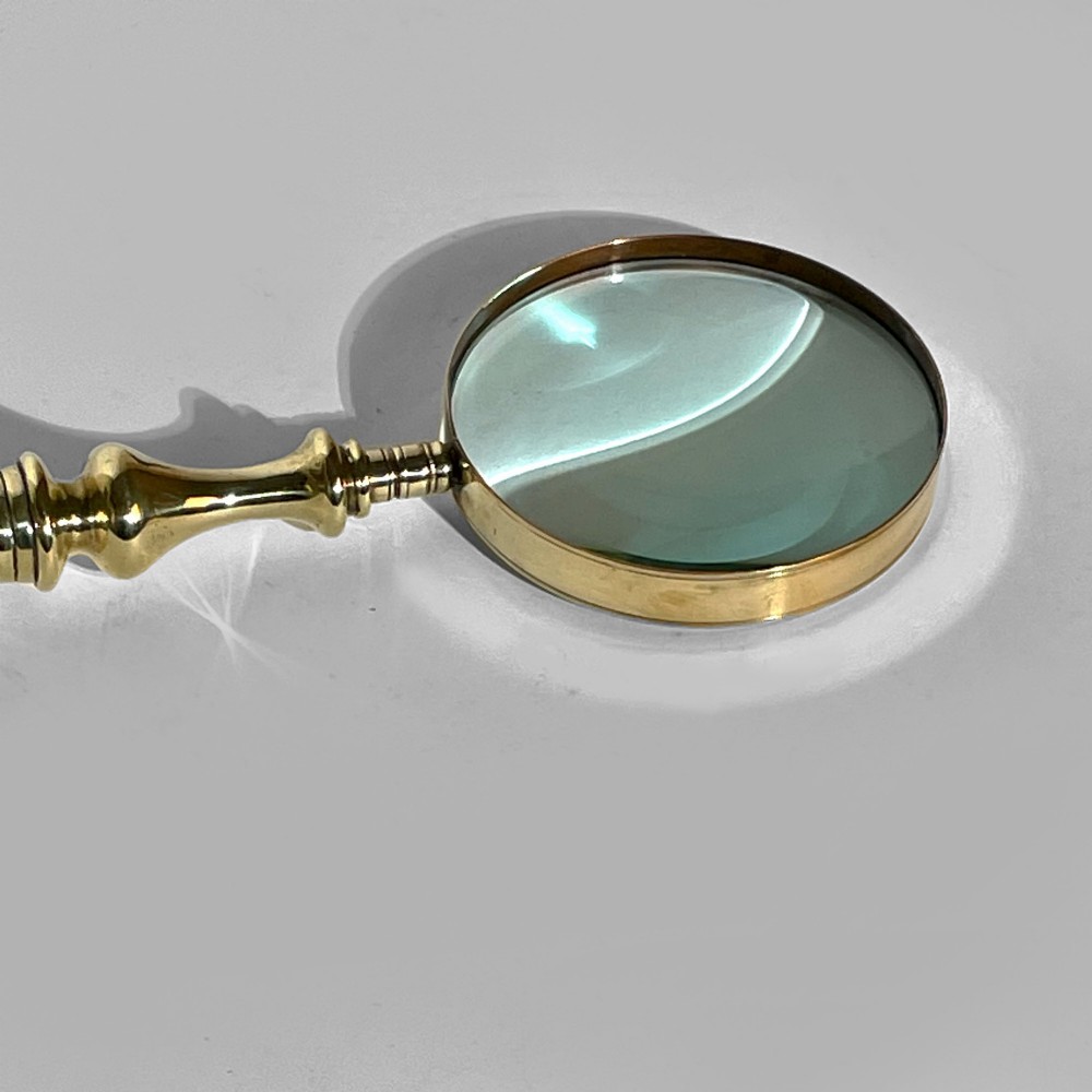A 19th-century brass magnifying glass featuring a turned handle with a spherical finial and a circular convex lens. View III