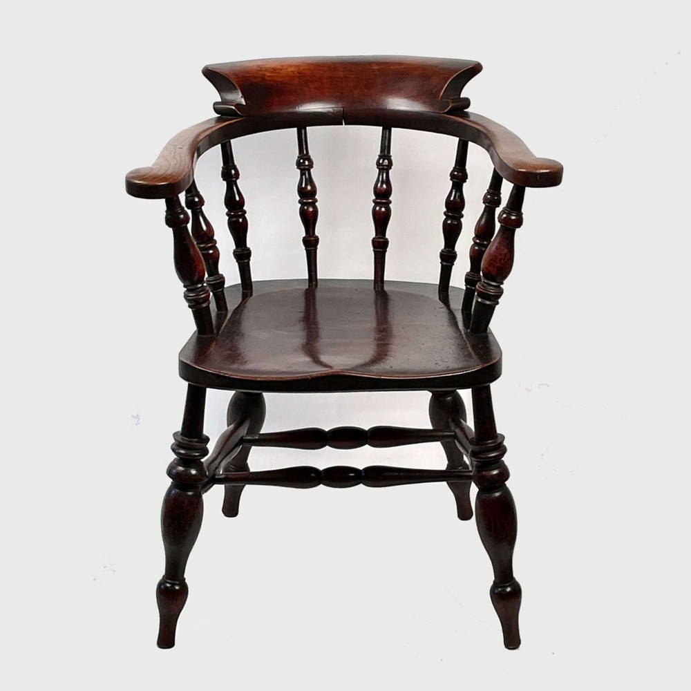 A nineteenth-century dark-stained ash and elm Windsor armchair featuring turned spindles, a curved arm rail, a saddle seat, and turned legs with stretchers. View III