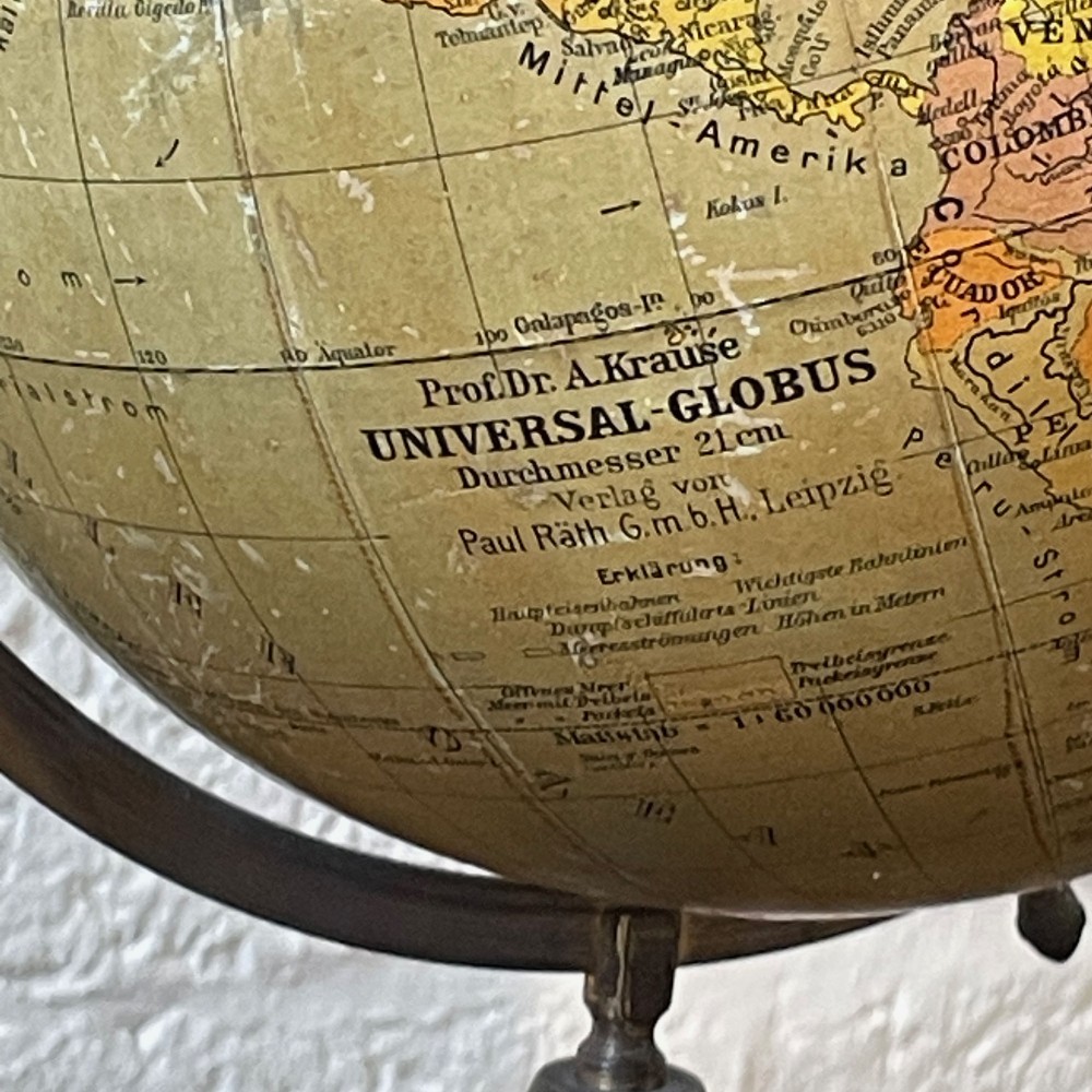 An early 20th-century German terrestrial desk globe featuring printed paper map gores, a graduated brass meridian ring, and a turned ebonised wooden base. View II