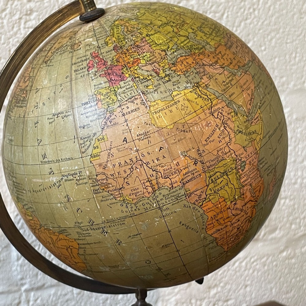 An early 20th-century German terrestrial desk globe featuring printed paper map gores, a graduated brass meridian ring, and a turned ebonised wooden base. View III