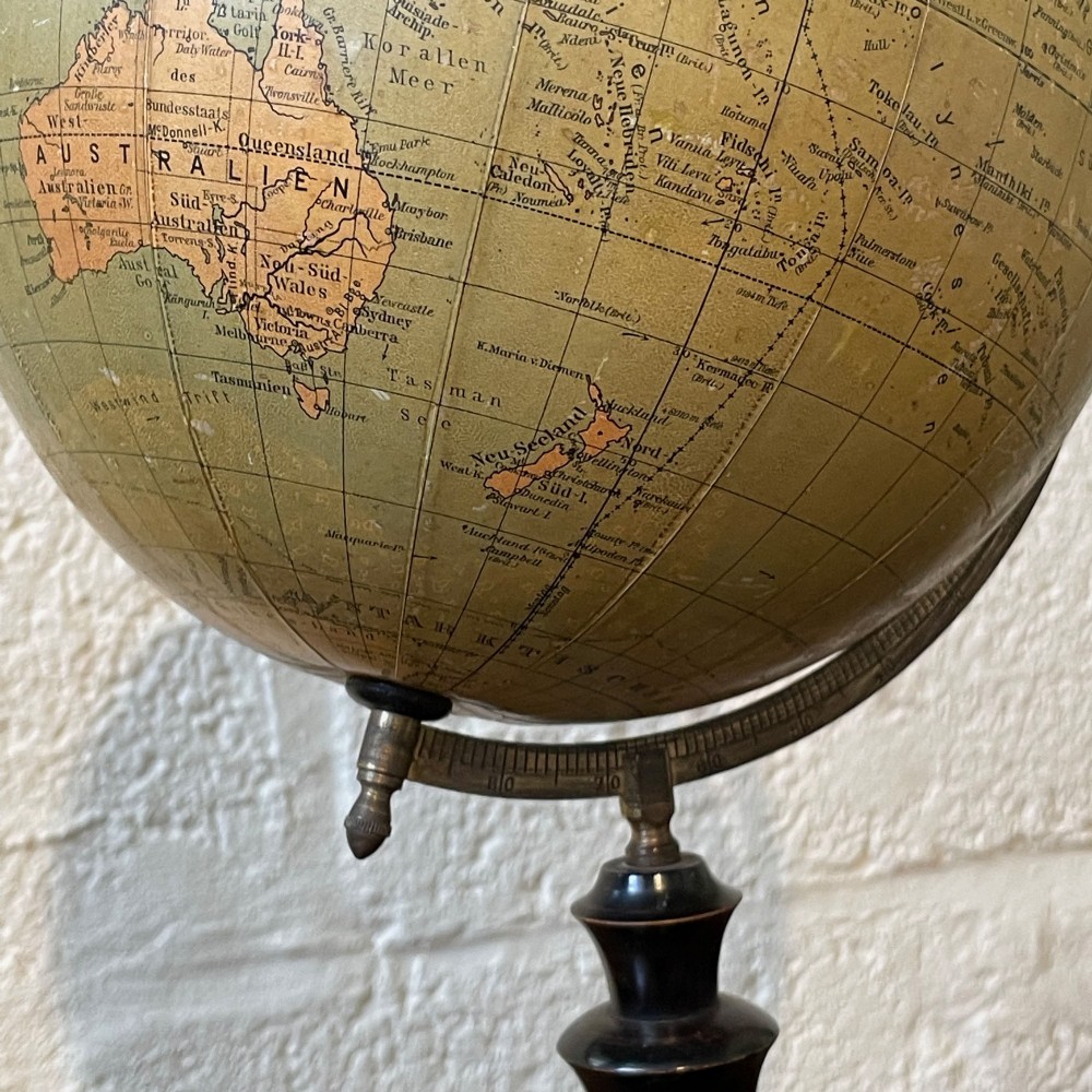 An early 20th-century German terrestrial desk globe featuring printed paper map gores, a graduated brass meridian ring, and a turned ebonised wooden base. View IV