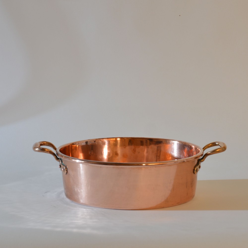 A wide circular 19th-century polished copper preserving pan with a rolled rim and twin riveted handles.