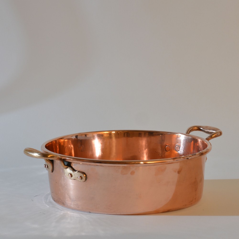 A wide circular 19th-century polished copper preserving pan with a rolled rim and twin riveted handles. View II