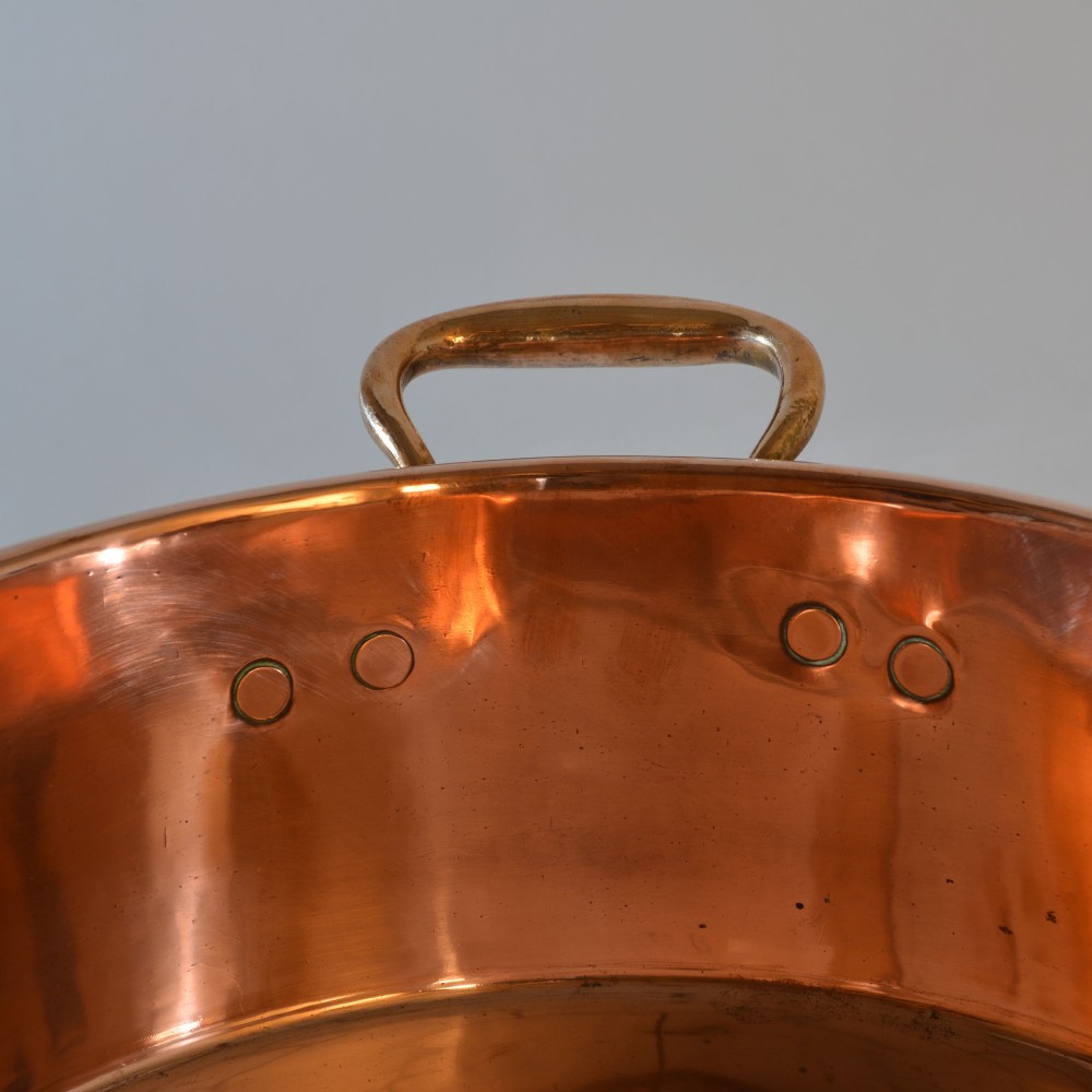 A wide circular 19th-century polished copper preserving pan with a rolled rim and twin riveted handles. View V