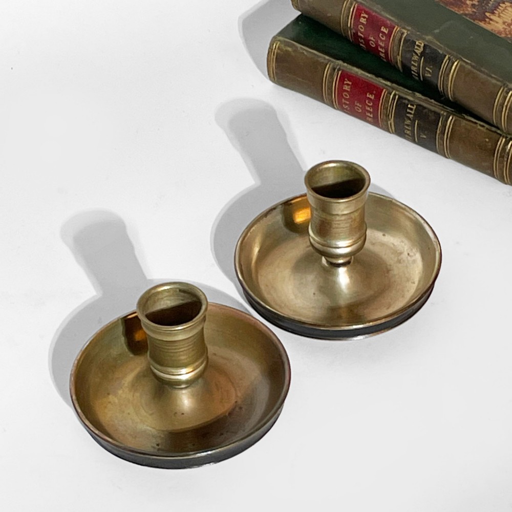 A pair of 19th-century brass travelling candlesticks disassembled next to their black leather-bound circular casing. View II
