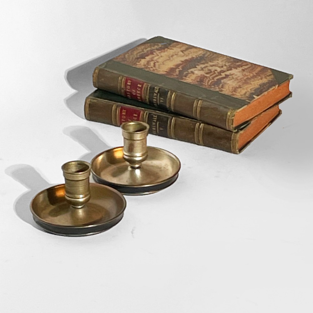 A pair of 19th-century brass travelling candlesticks disassembled next to their black leather-bound circular casing. View III
