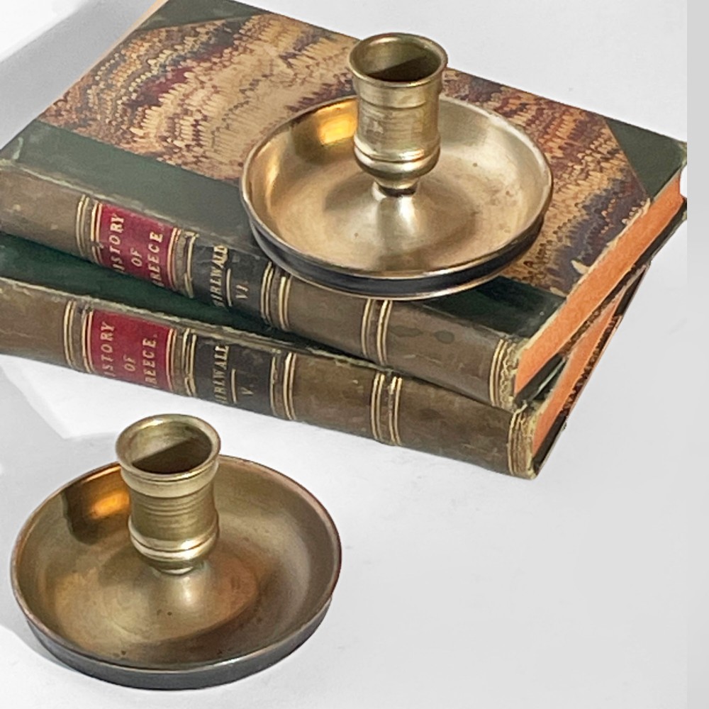 A pair of 19th-century brass travelling candlesticks disassembled next to their black leather-bound circular casing. View IV