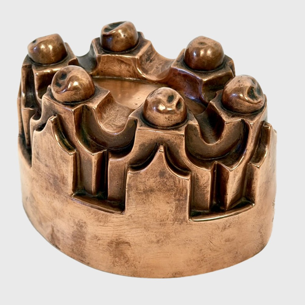 A 19th century oval copper jelly mould featuring raised turrets and orb details on a stepped base.