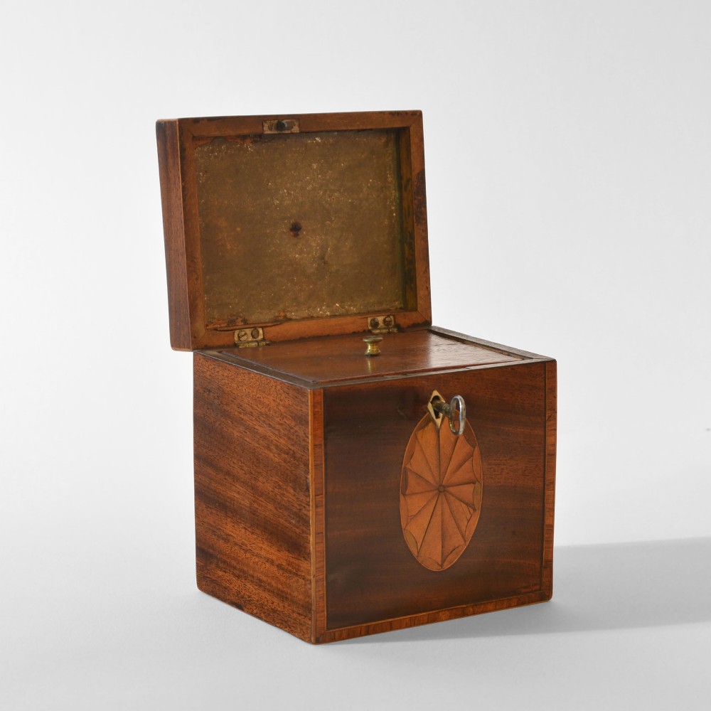 An 18th-century Sheraton mahogany square tea caddy with a top brass handle, key in lock, and an oval inlaid shell motif on the front. View III