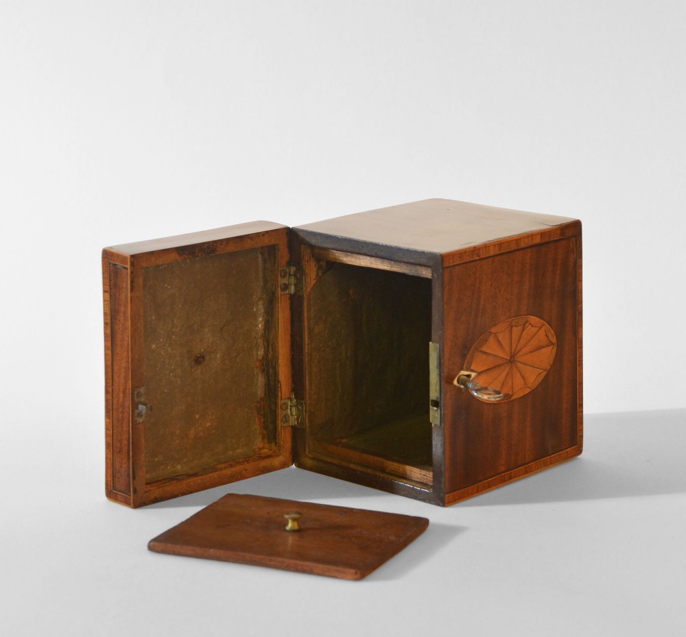 An 18th-century Sheraton mahogany square tea caddy with a top brass handle, key in lock, and an oval inlaid shell motif on the front. View VI