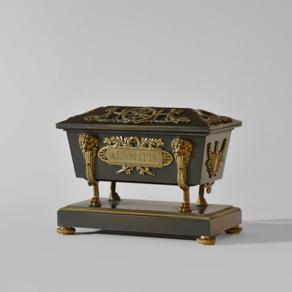 An 18th-century French Directoire casket-form inkstand in patinated black metal and gilt bronze, supported on lion monopodia legs with a inscribed plaque.