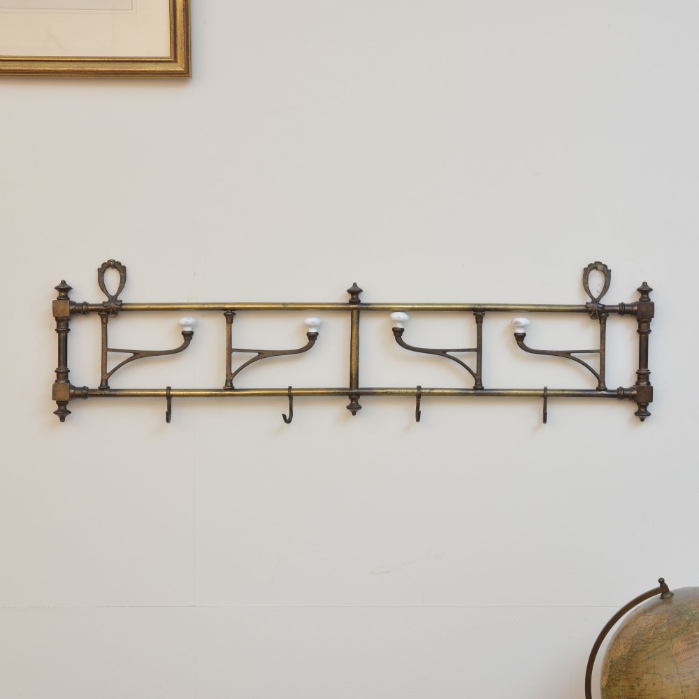 A wall-mounted aged brass coat rack featuring two horizontal bars, four ceramic-tipped upper hooks, and four hanging lower hooks. View II