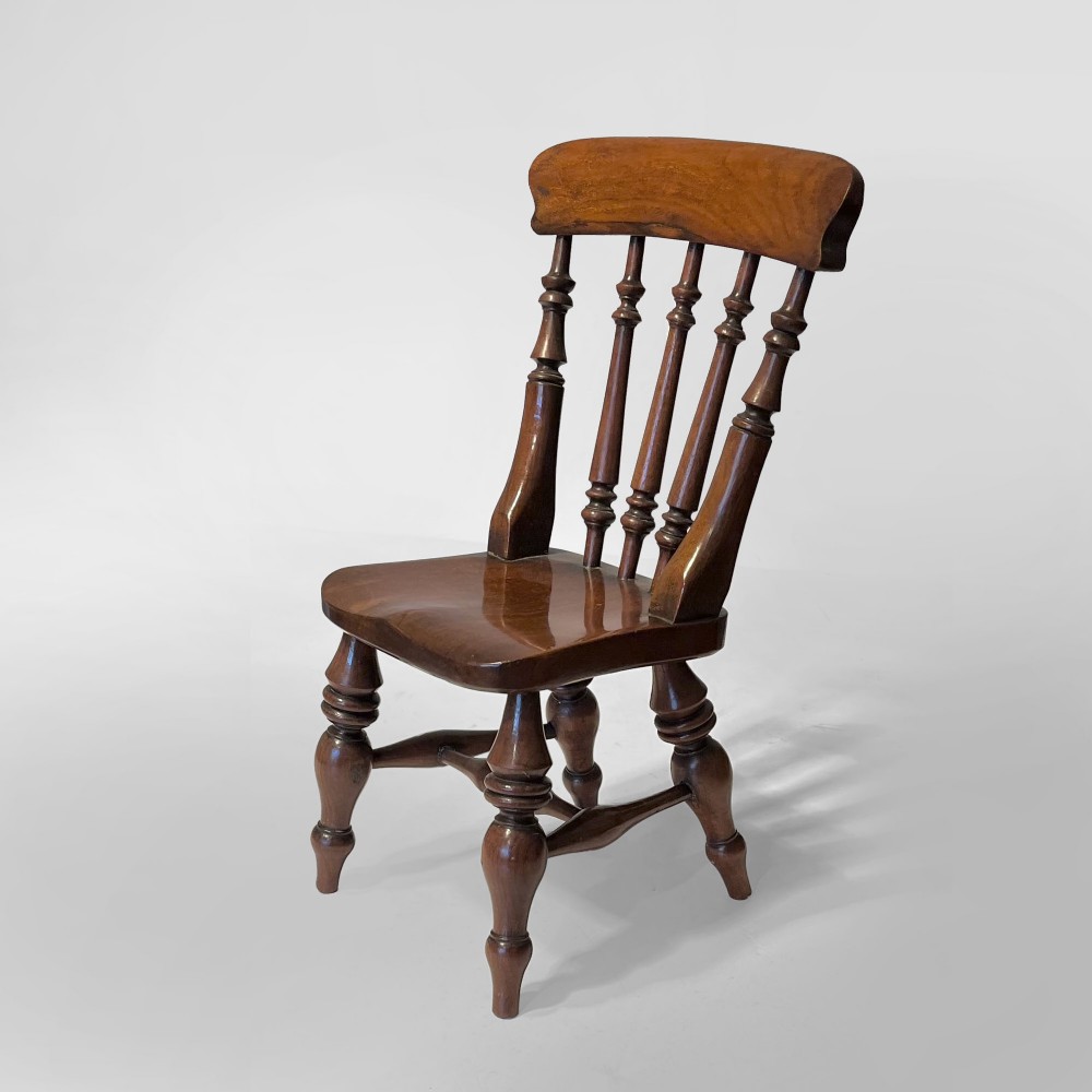 A 19th-century miniature wooden Windsor chair with turned spindles, a curved top rail, a contoured seat, and a small accompanying turned stool. View II