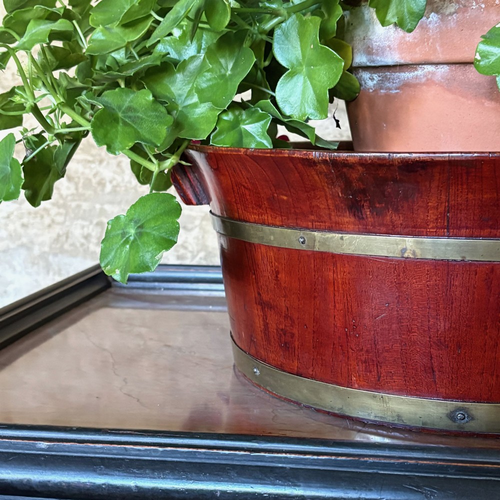 An oval 19th-century mahogany coopered jardiniere featuring horizontal brass binding bands and integrated wooden handles. View II