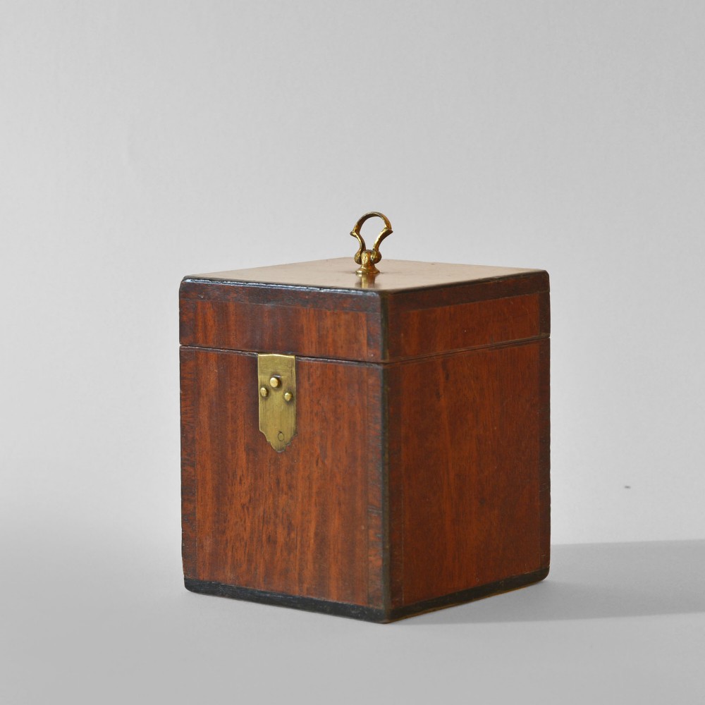 A cubic Georgian mahogany tea caddy featuring a brass loop handle on the top lid and a brass latch on the front.