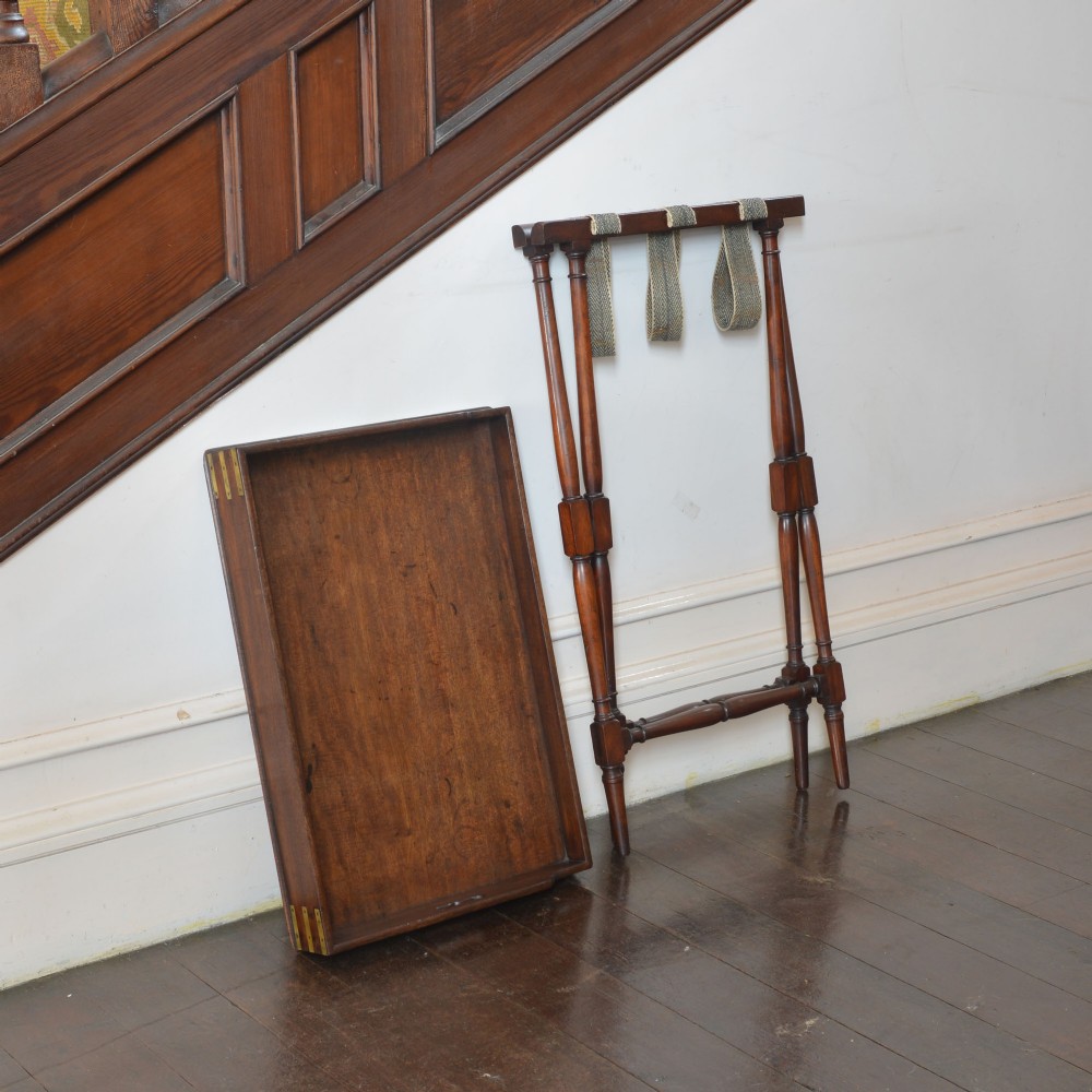 An antique dark mahogany butler tray with gallery edges and brass corner brackets set atop a folding x-frame stand with turned wooden legs. View II