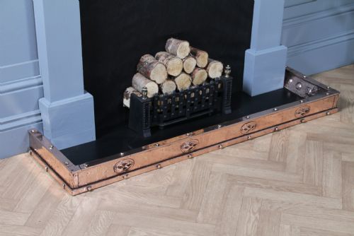 fig 1. A low polished copper fireplace fender curb featuring hand-riveted edges and decorative embossed oval motifs around the perimeter.