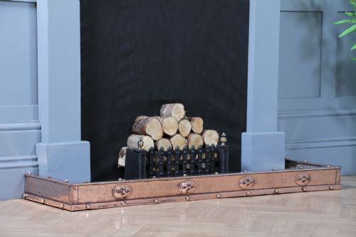 fig 2. A low polished copper fireplace fender curb featuring hand-riveted edges and decorative embossed oval motifs around the perimeter.