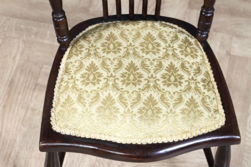 fig 2. An Edwardian dark walnut nursing chair featuring a spindled stick back, turned legs, and a patterned yellow fabric seat.