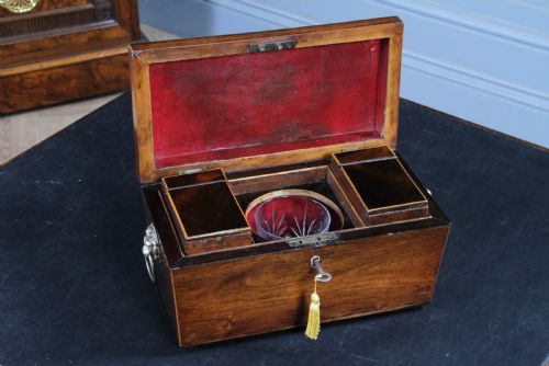 fig 1. A Georgian rosewood sarcophagus-form tea caddy featuring stringing inlay, brass lion-mask side handles, and a keyhole with a tasselled key.