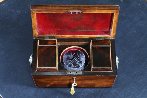 fig 2. A Georgian rosewood sarcophagus-form tea caddy featuring stringing inlay, brass lion-mask side handles, and a keyhole with a tasselled key.