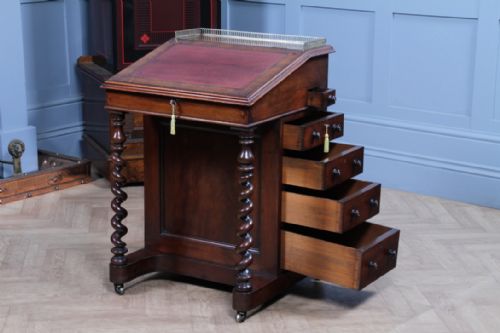 fig 1. An early Victorian mahogany Davenport desk featuring a sloped writing surface with red leather inset, brass top gallery, barley twist front supports, and four side drawers.