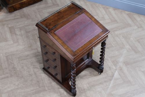 fig 2. An early Victorian mahogany Davenport desk featuring a sloped writing surface with red leather inset, brass top gallery, barley twist front supports, and four side drawers.